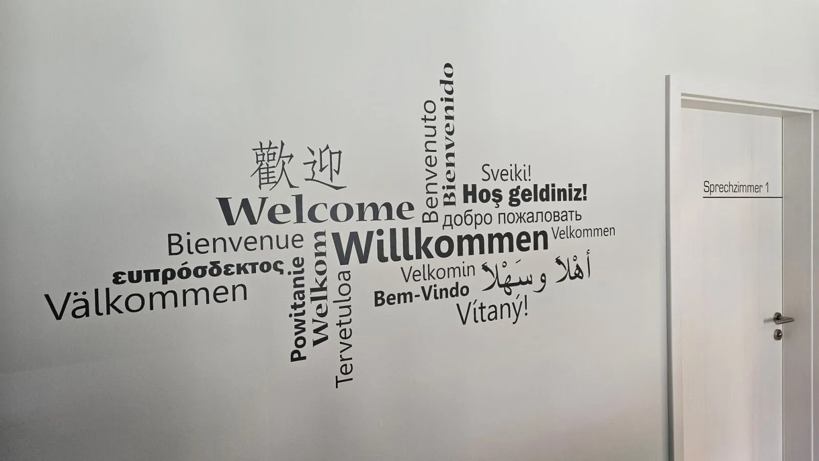 Willkommens-Schriftzug in vielen Sprachen an der Wand